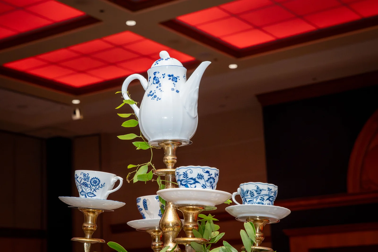 Porcelain tea set on a gala table under a red coffered ceiling